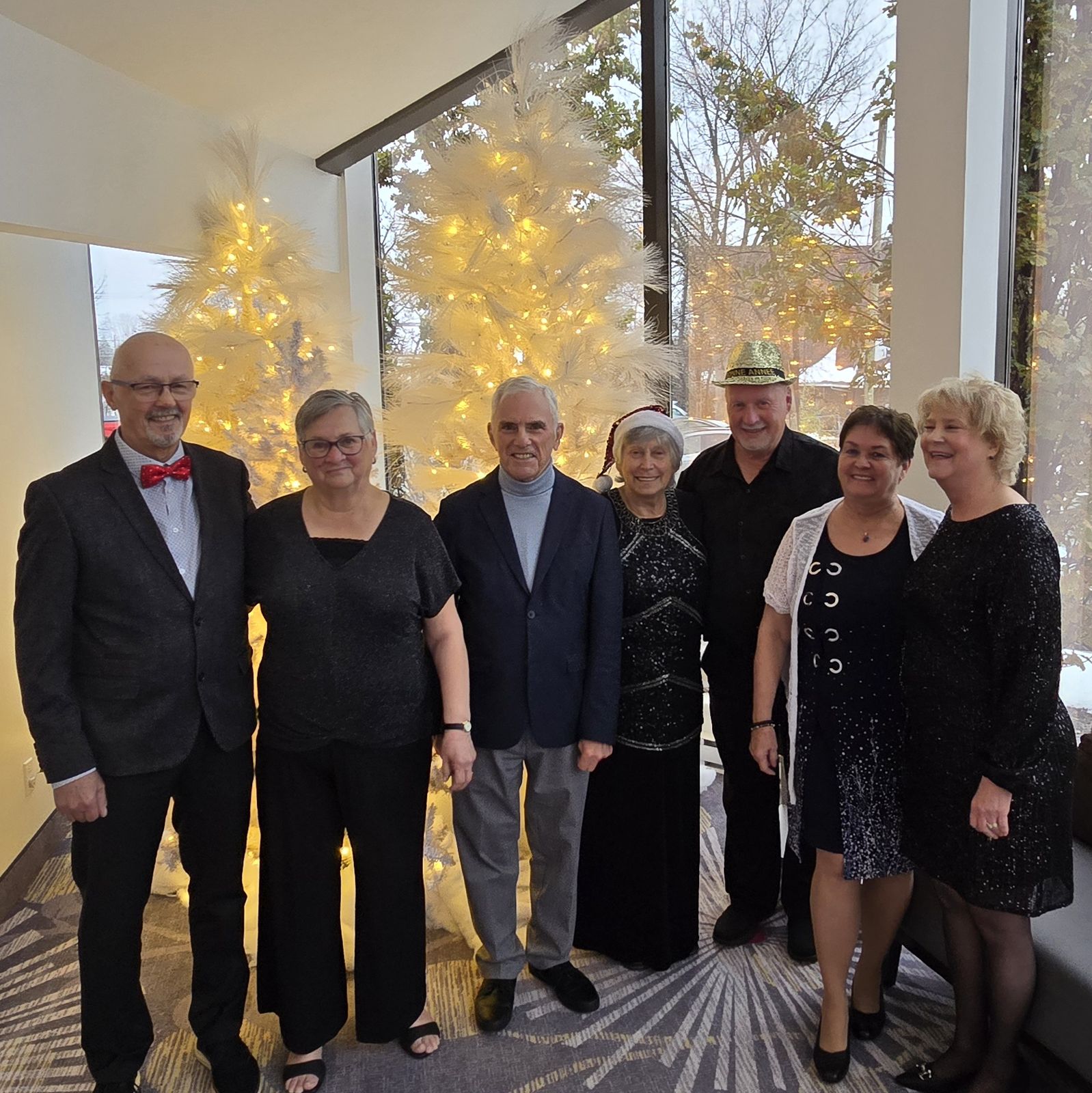Les sept membres du conseil d'administration du Club, en tenue de soirée, devant un sapin de Noël.
